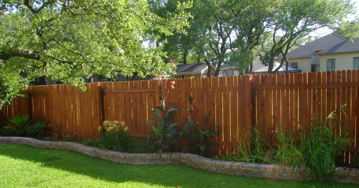 A freshly stained honey-cedar privacy fence along a Denver backyard garden